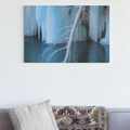 Gray sofa with decorative pillows and a blanket, featuring a large wall art of icy landscape.